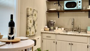 A kitchen with white cabinets, a wooden ceiling, a microwave, and a potted plant.
