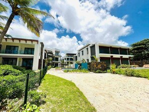 A modern hotel with multiple buildings, a well-maintained lawn, and a clear sky. - Exclusive beachfront penthouse (Belle Mare)