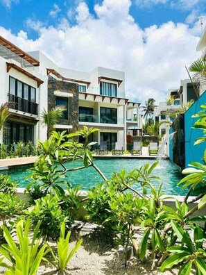 A resort with a swimming pool, multiple-story buildings, and tropical landscaping. - Exclusive beachfront penthouse (Belle Mare)