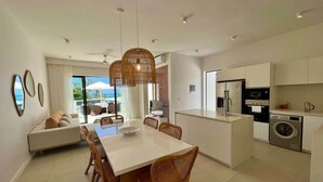 A modern kitchen with a dining area, a sofa, and a view of the outdoors. - Exclusive beachfront penthouse (Belle Mare)