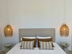 Un dormitorio con una cama, dos mesitas de noche y dos lámparas de pared.