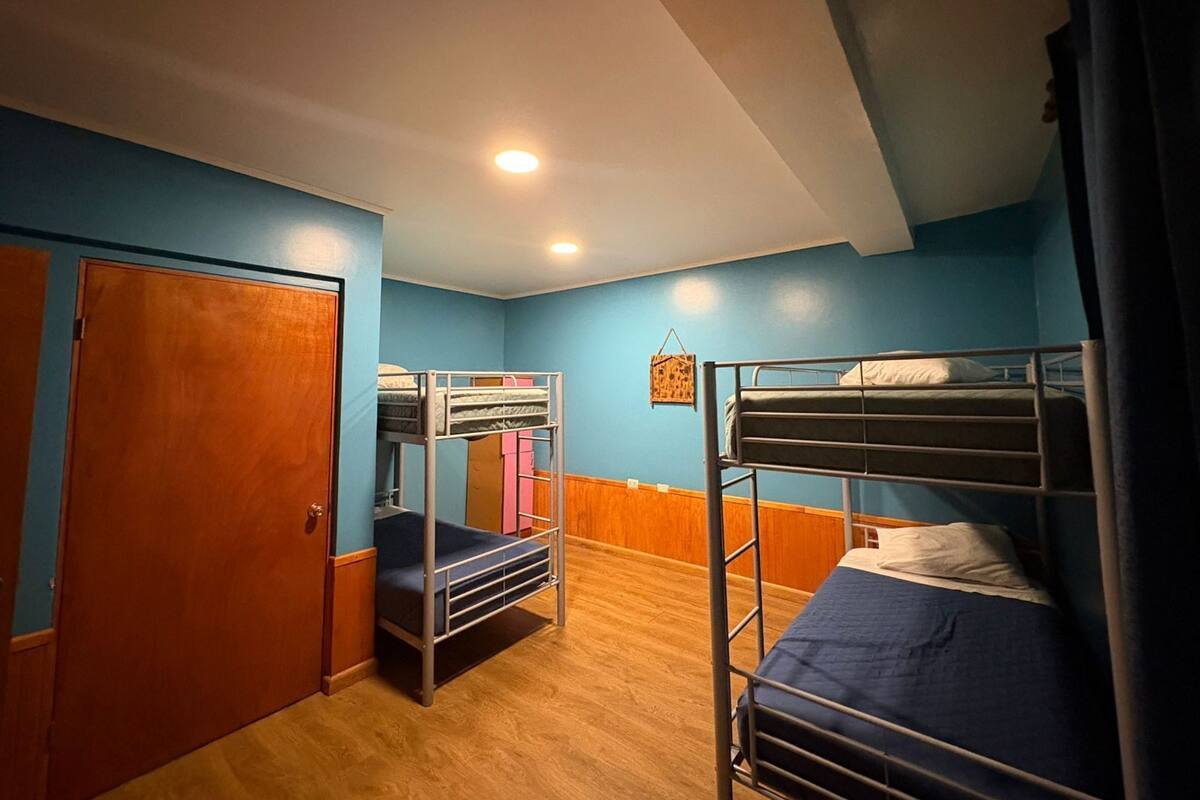 Ein Zimmer mit Etagenbetten, einer Holztür und einem kleinen Wandbild.