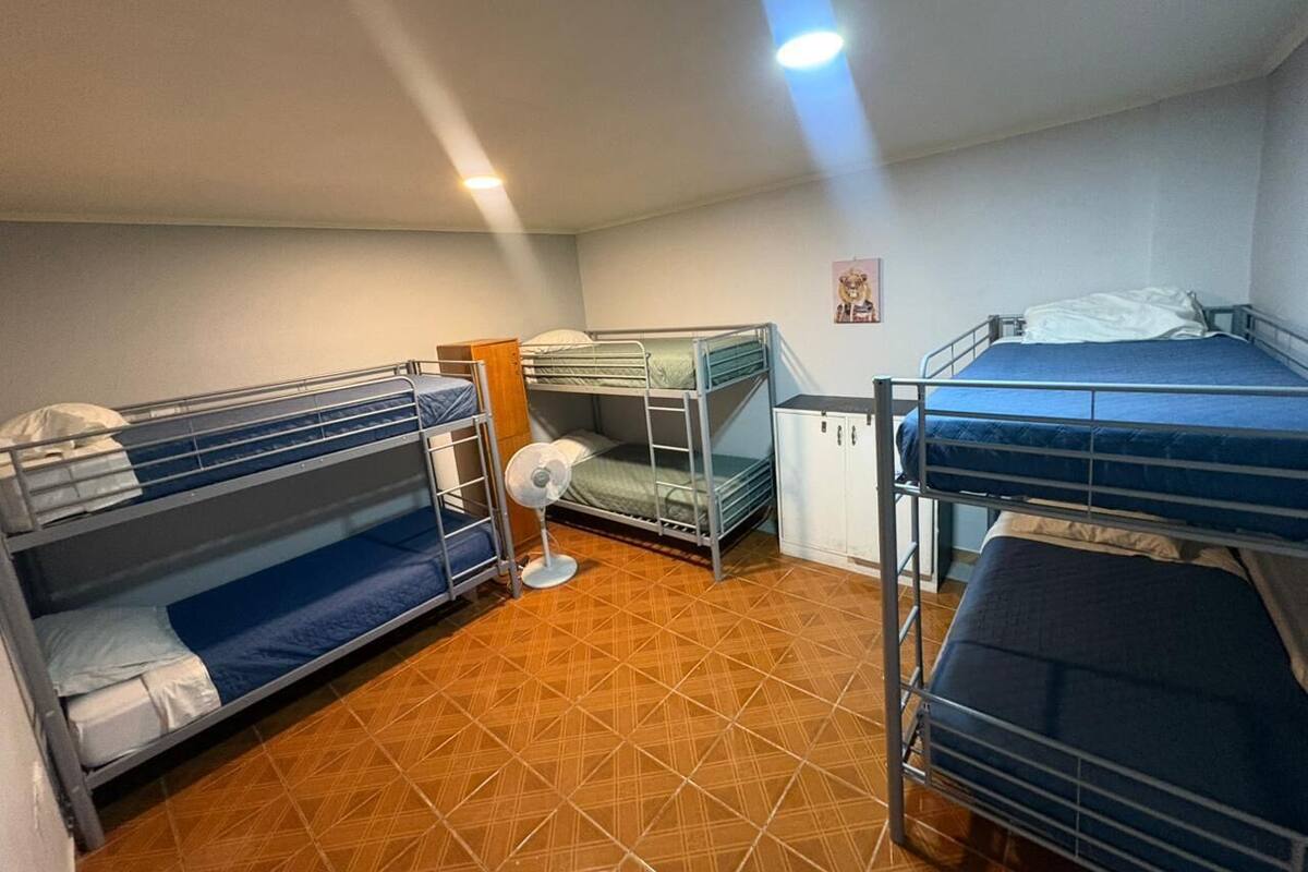 Ein Schlafsaalzimmer mit Etagenbetten, einem Ventilator und einem Schrank.