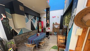 An outdoor patio with a table and chairs, surrounded by potted plants and a decorative wall. - Raymi House Hostel (Arica)