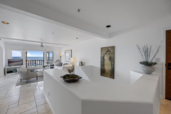 A modern living room with a white reception desk, a large painting, and a potted plant. - H882: Beautiful 1Bd Townhouse style villa + Golf Cart+ 2 Private Balconies (Avalon)