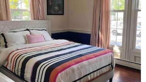 Une chambre avec un grand lit, une table de chevet et une fenêtre avec des rideaux.