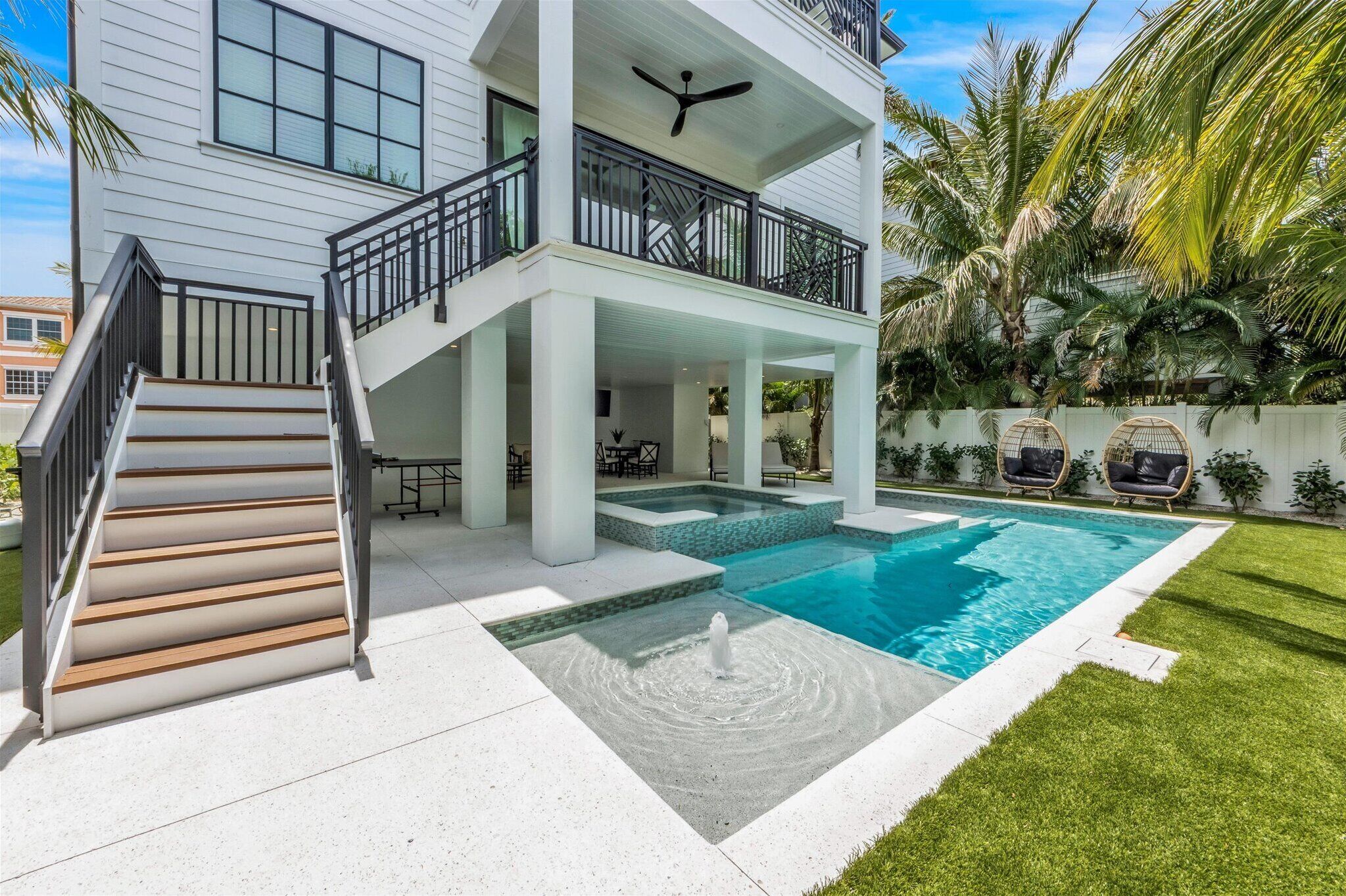 Une maison à deux étages avec une piscine, un balcon et un escalier.
