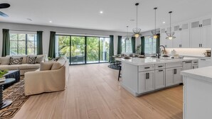 Een moderne keuken met witte kasten, een centraal eiland en hanglampen.