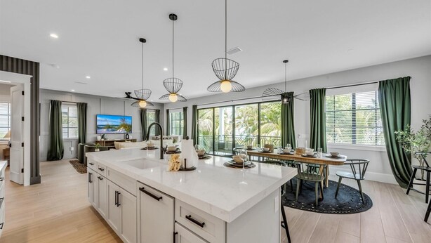 Een moderne keuken met een groot eiland, hanglampen en een eetgedeelte met uitzicht.
