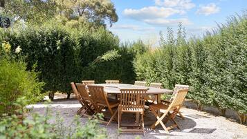 Une table ronde en bois, entourée de six chaises, dans un jardin.
