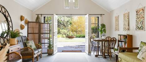 A spacious room with a high ceiling, a dining area, and a cozy seating area with a sofa and chairs.