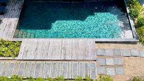 A rectangular swimming pool with clear water, surrounded by a wooden deck and stone tiles. - Breathtaking seaview penthouse (Belle Mare)
