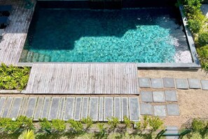 A rectangular swimming pool with clear water, surrounded by a wooden deck and stone tiles. - Breathtaking seaview penthouse (Belle Mare)