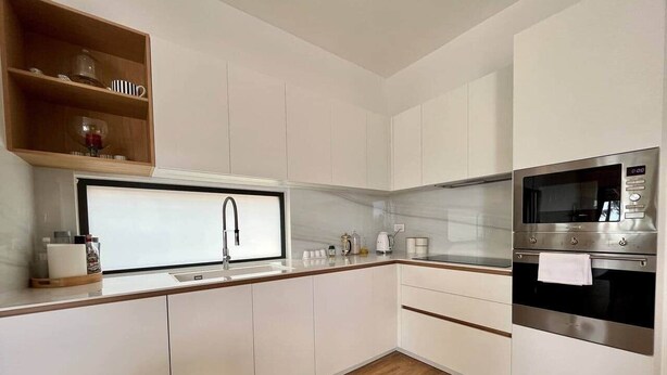 A modern kitchen with white cabinetry, a stainless steel oven, and a window above the sink. - Breathtaking seaview penthouse (Belle Mare)