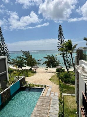 Un espace piscine offrant une vue dégagée sur l’océan et la plage.