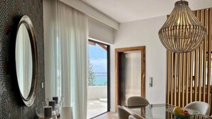 A modern dining area with a glass table, chairs, and a decorative chandelier. - Breathtaking seaview penthouse (Belle Mare)