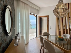 Ein moderner Essbereich mit einem Glastisch, Stühlen und einer dekorativen Chandelier.