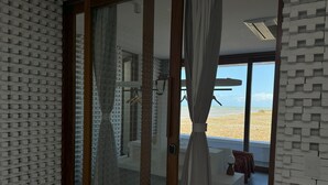 A room with a beach view, a sliding glass door, and a modern bathroom with a shower.