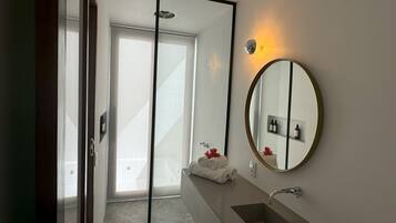 A modern bathroom with a large mirror, a sink, and a towel rack.
