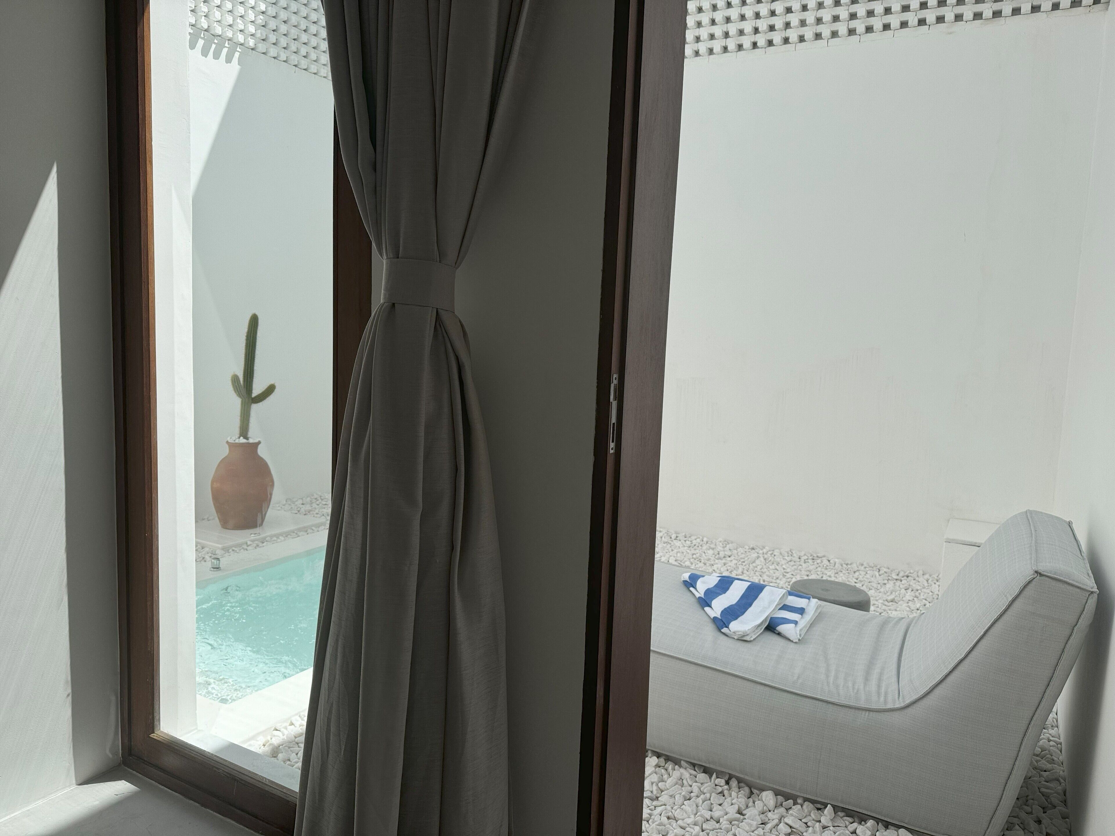 Una habitación con vista a una piscina, un cactus y un área de descanso con una toalla a rayas.