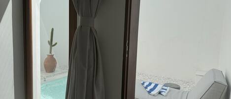 Una habitación con vista a una piscina, un cactus y un área de descanso con una toalla a rayas.