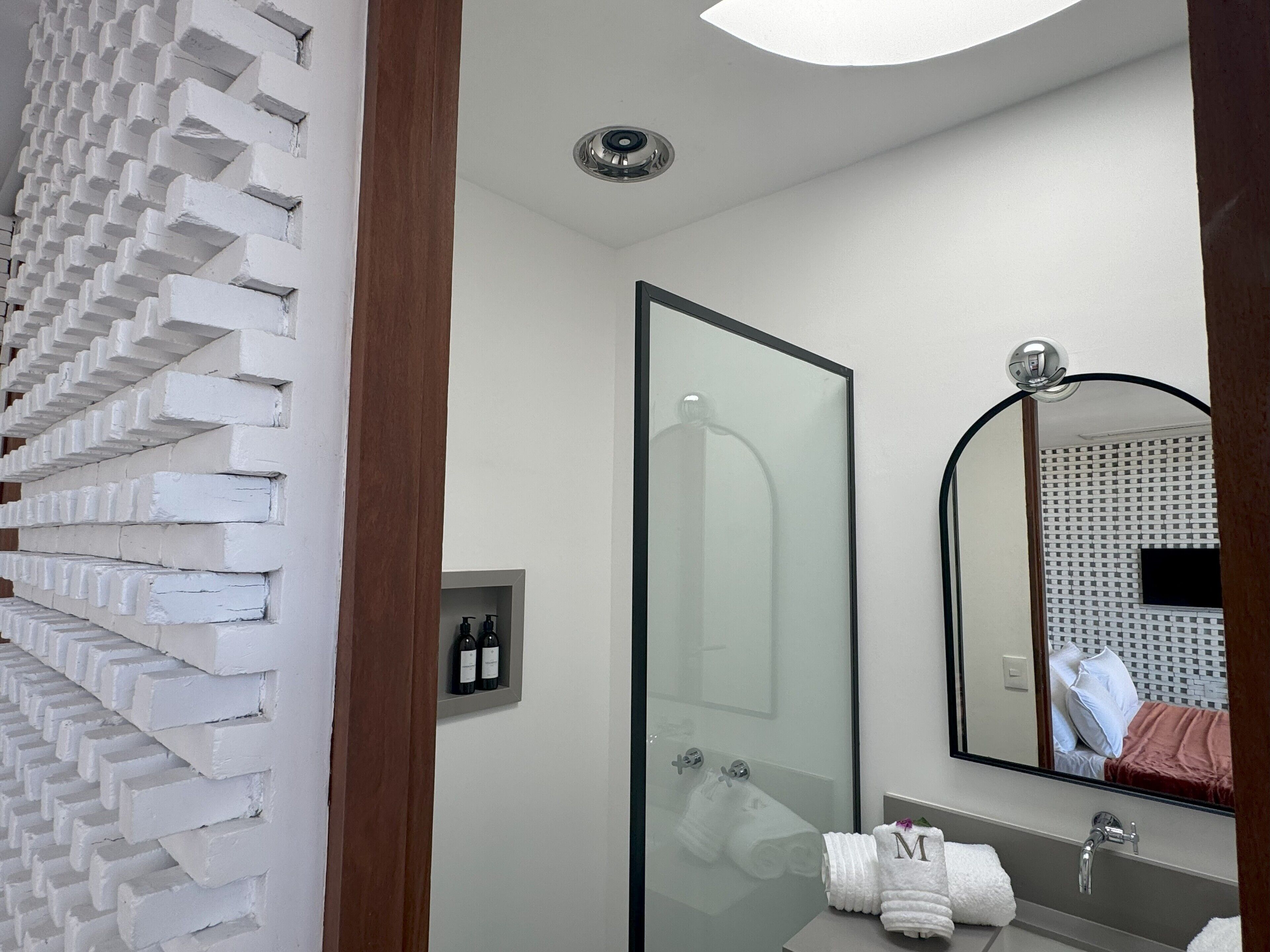 A modern bathroom with a glass shower enclosure, a large mirror, and a sink with two towels.