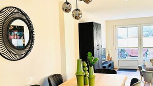 Un comedor con una mesa de madera, jarrones verdes y sillas negras.