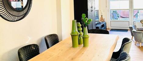A dining area with a wooden table, green vases, and black chairs.