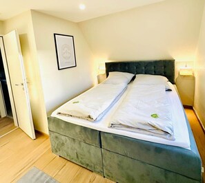A double bed with a dark headboard, two bedside lamps, and a framed picture on the wall.