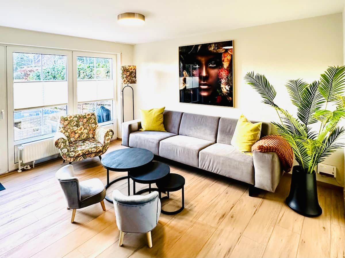 A modern living room with a sofa, armchairs, a coffee table, and a large window.