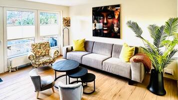 A modern living room with a sofa, armchairs, a coffee table, and a large window.
