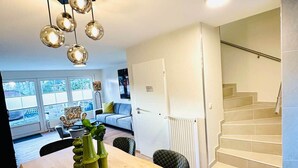 Un interior moderno con comedor, una escalera y vistas a través de amplias ventanas.