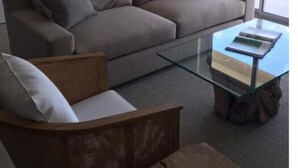 A modern living room with a grey sofa, a glass coffee table, and a wooden side table. - Luxury Suite 2.4 in Seneca, Point Blanche, St Maarten (Point Blanche)