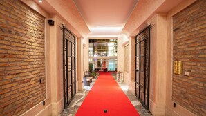 A hallway with a red carpet, brick walls, and black gates leading to a room with a large window and a plant.