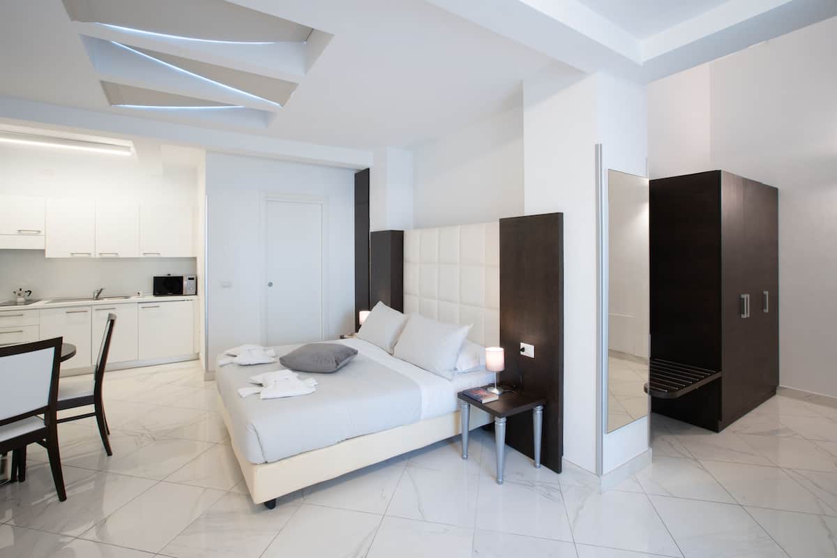Ein modernes Hotelzimmer mit Bett, Nachttisch und integriertem Kleiderschrank.