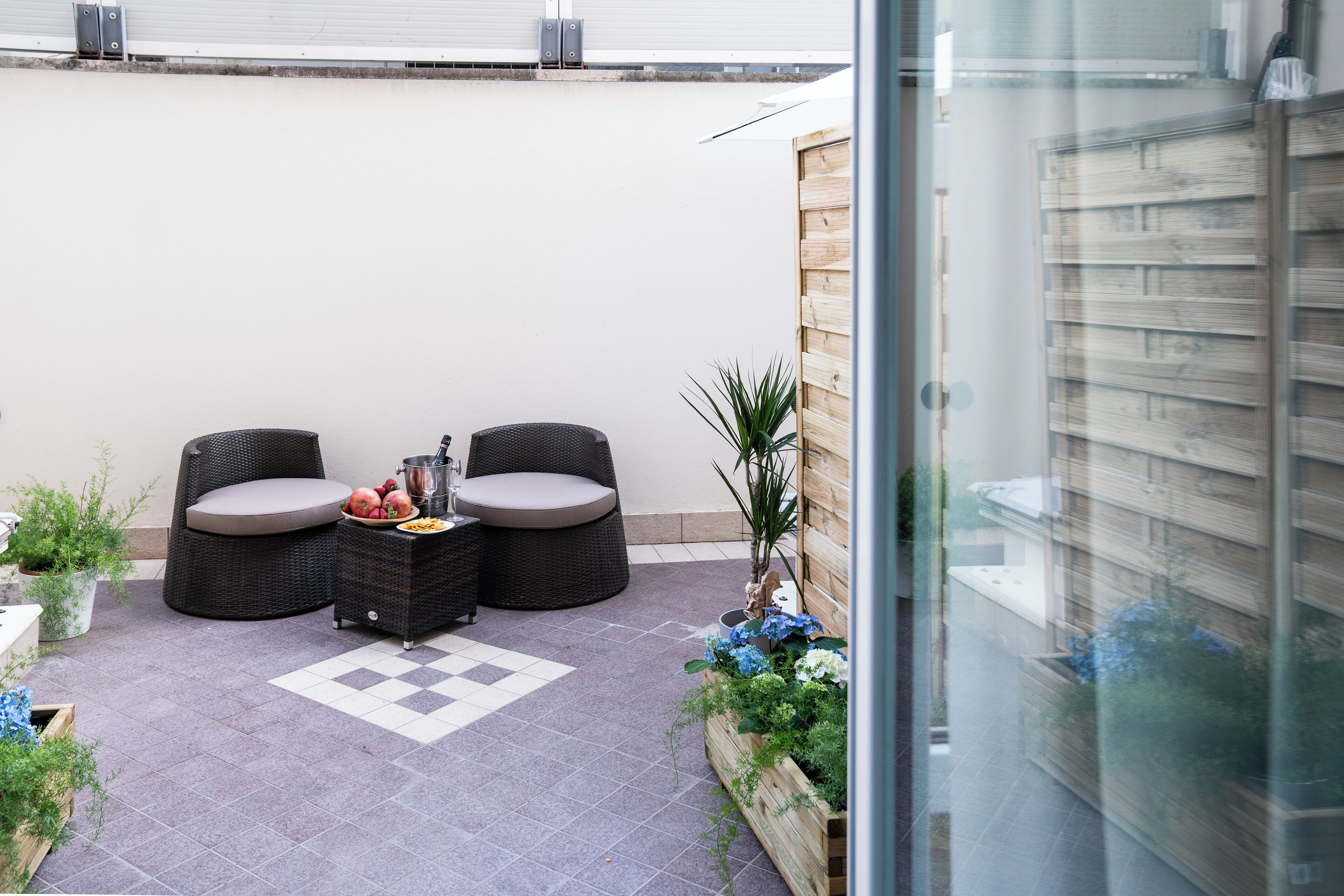 A patio area with wicker furniture, a checkered floor, and potted plants.