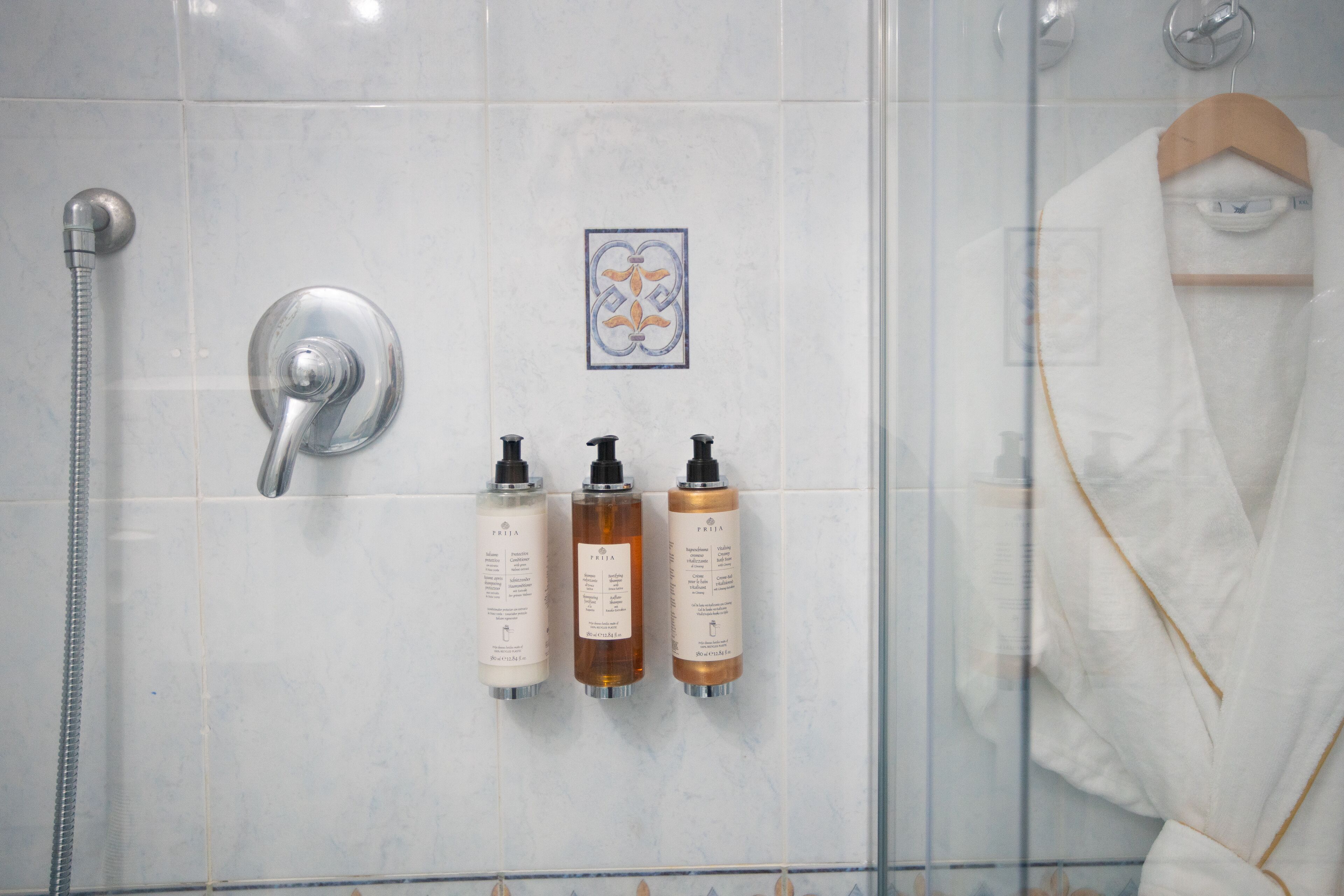 Een badkamer met een douche, drie toiletartikelen en een handdoekhouder.