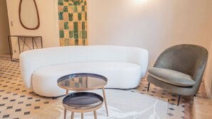 A modern living room with a white sofa, a round glass table, and a grey armchair. - Le Pavillon, Appartement Écolodge Haut de Gamme Avec Piscine et Jacuzzi (Pézenas)