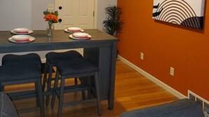 A dining area with a table set for four, a sofa, and a painting on the wall. - Cozy 2 Bedroom with King Bed, 2 Full Bathrooms Conveniently located in the heart of Muskegon!!! (Muskegon)
