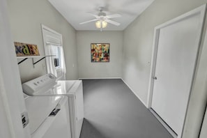A laundry room with a ceiling fan, a wall-mounted artwork, and a door.