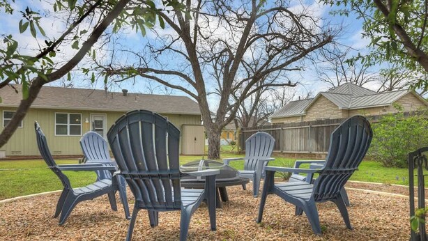 Un patio con sillas Adirondack y una mesa de vidrio rodeada de piedras pequeñas.