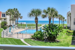 A pool area with a view of the ocean, surrounded by palm trees and a fence. - Pier Point 36 (St. Augustine)