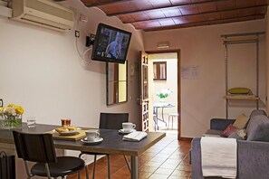 A dining area with a table, chairs, a TV mounted on the wall, and a sofa. - BeBarceloner Gothic Quarter Studios (Barcelona)