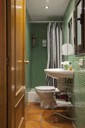 A bathroom with a green tiled wall, a white sink, a toilet, and a shower curtain. - BeBarceloner Gothic Quarter Studios (Barcelona)
