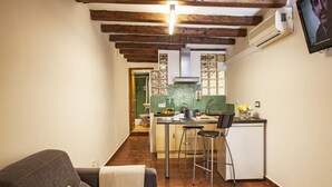 A compact kitchen with a dining area, a small refrigerator, and a TV mounted on the wall. - BeBarceloner Gothic Quarter Studios (Barcelona)