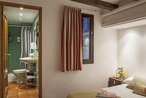 A bedroom with a bed, a nightstand with a lamp, and a window with curtains. - BeBarceloner Gothic Quarter Studios (Barcelona)
