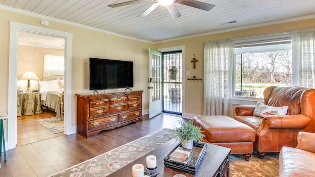 A living room with a ceiling fan, a television, a leather sofa, and a wooden cabinet.
