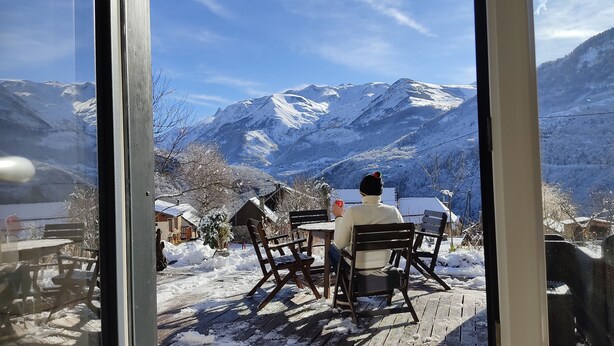Une personne assise à une table, avec une vue sur la montagne.