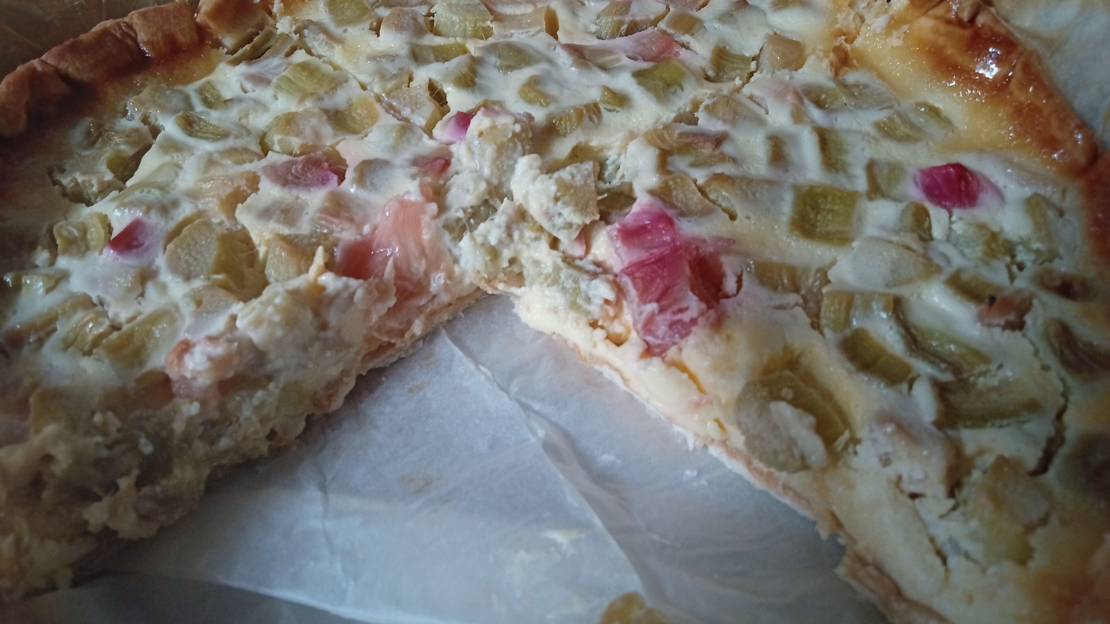 A close-up of a pizza with various toppings, including cheese, vegetables, and possibly meat.