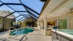 Une piscine extérieure couverte, dotée d’un jacuzzi, de chaises longues et d’un ventilateur de plafond.